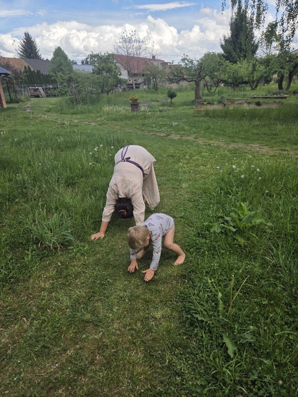 Dospělý a dítě společně cvičí pohybovou hru na zahradě